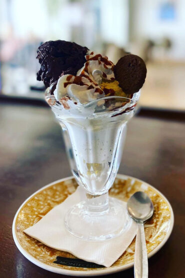 Copa de helado de chocolate, brownie, galletas y nata con caramelo